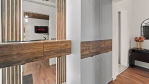 Een modern interieur met een houten bureau, een spiegel en een aan de muur bevestigde televisie waarop 'NETFLIX' staat.