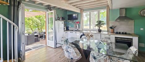 A modern kitchen with a glass dining table, white cabinets, and a built-in stove.