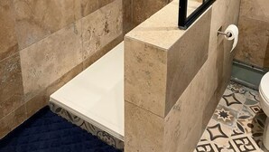 Et moderne badeværelse med bruseniche, badekar og toilet.
