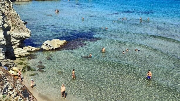 A coastal beach with clear water, rocky formations, and people swimming and walking along the shore. - Sweet World - Family Room with Terrace Near the Beach (Terrasini)