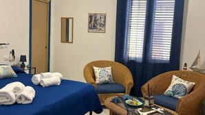 A room with a bed, two wicker chairs, a small table with a plate and a cup, and a window with curtains. - Sweet World - Family Room with Terrace Near the Beach (Terrasini)