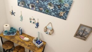 A room with a wooden table, chairs, a painting of sea life, and nautical decorations. - Sweet World - Family Room with Terrace Near the Beach (Terrasini)