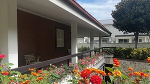 A covered outdoor area with a brick wall, a wooden bench, and a variety of colorful flowers. - Inn Rome B&B  (Rome)