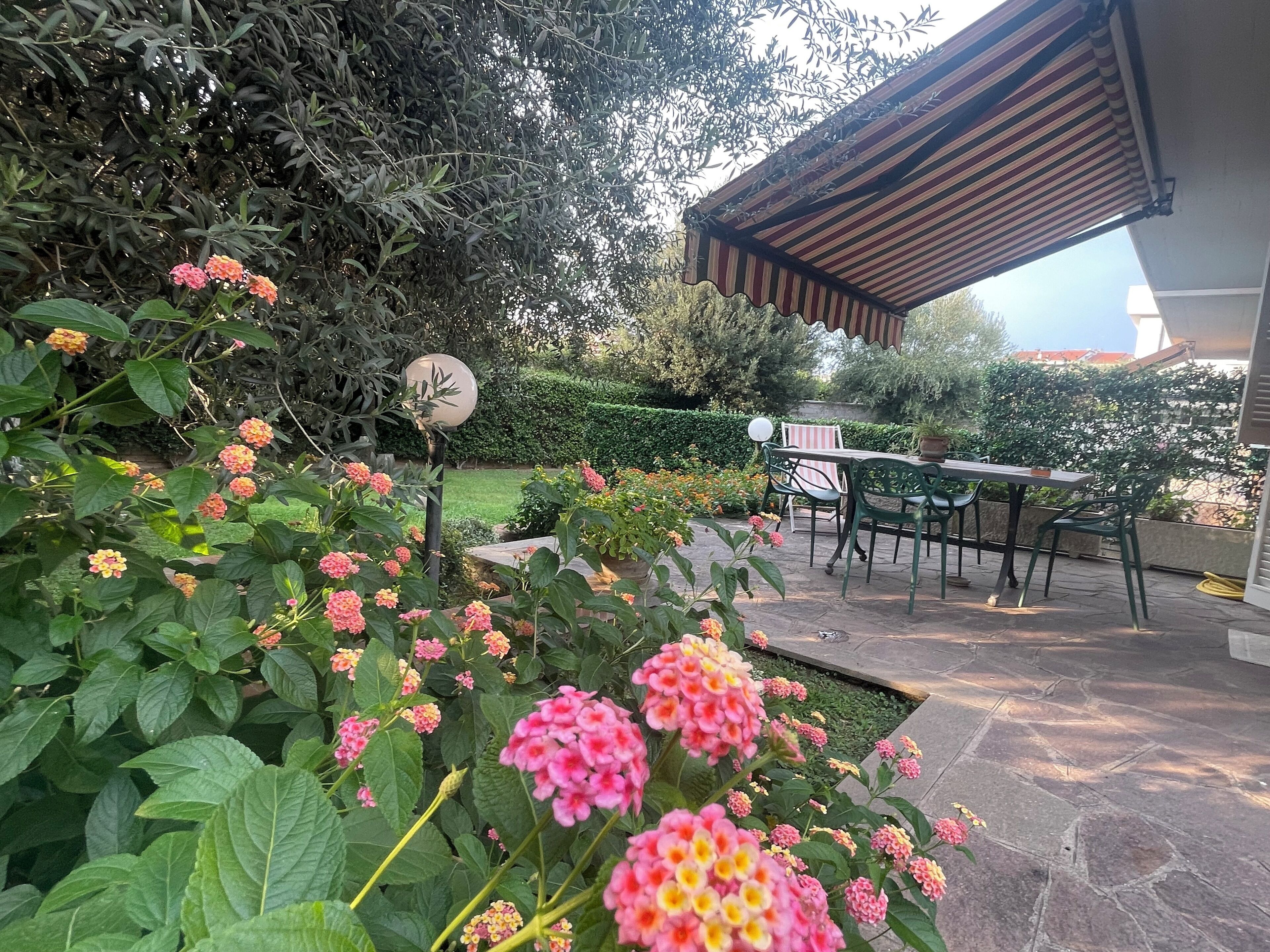 Un'area patio con tavolo e sedie, circondata da piante rigogliose e fiori.