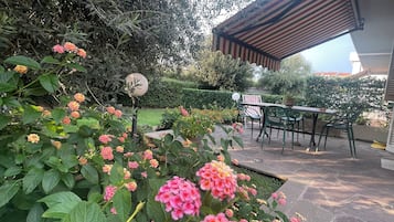 Un'area patio con tavolo e sedie, circondata da piante rigogliose e fiori.