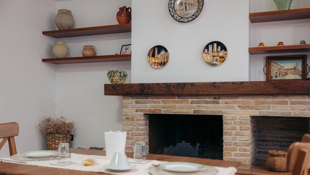 A dining area with a brick fireplace, wooden shelves with pottery, and a table set for two. - Inn Rome B&B  (Rome)