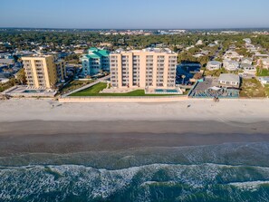 Un hotel frente a la playa con varias edificaciones, piscina y acceso directo a la costa.