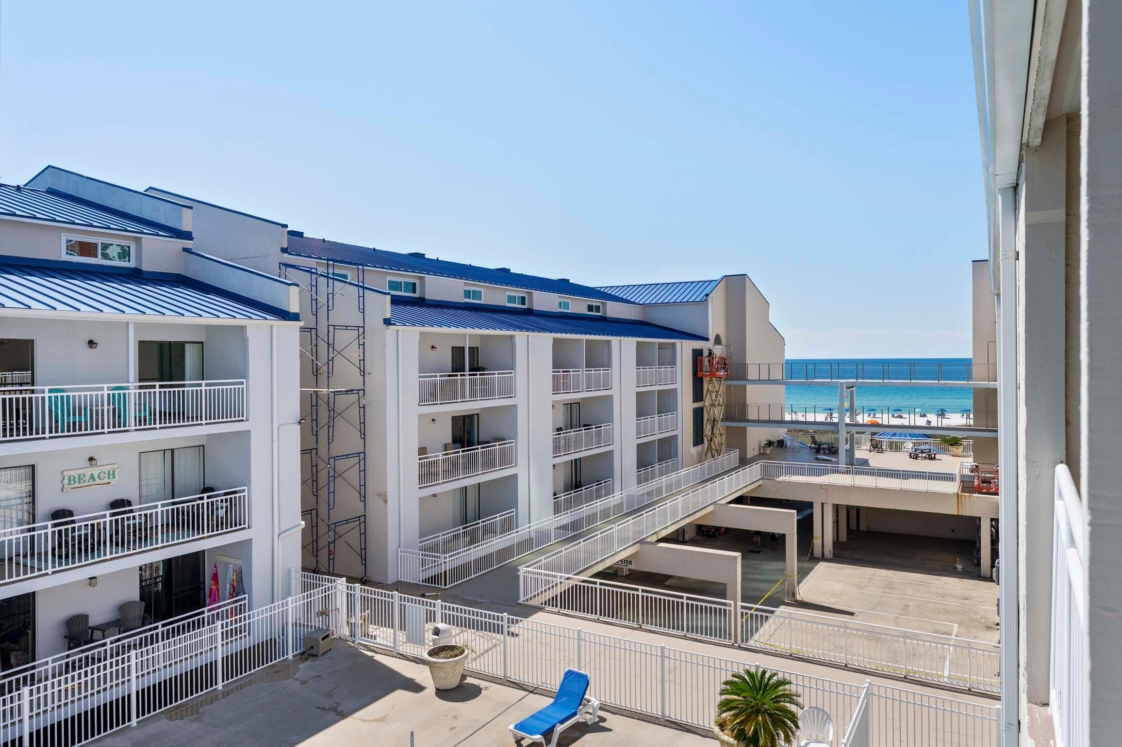 A multi-story hotel with balconies, a beach view, and a pool area.