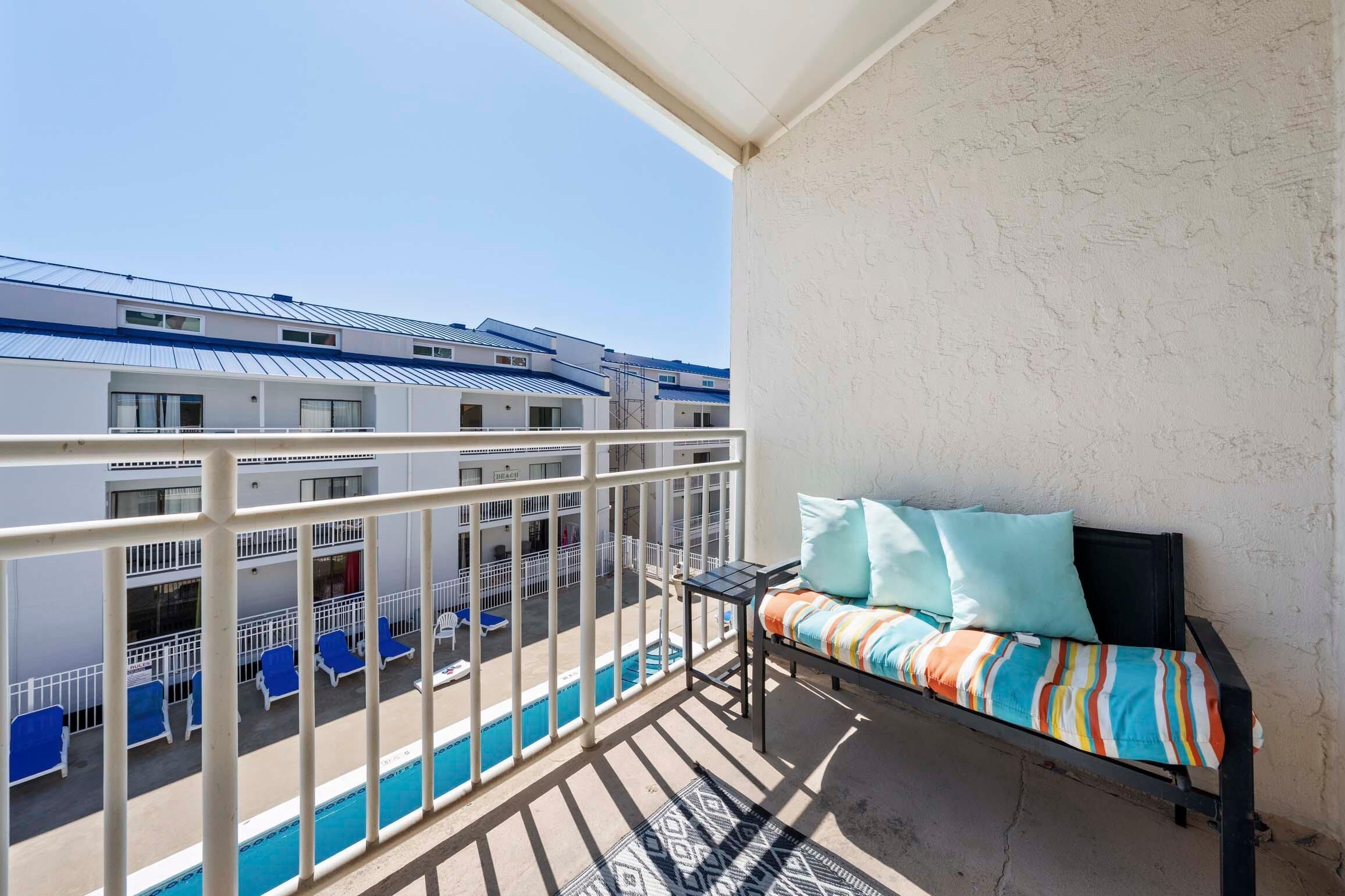 Un balcon avec une piscine, un canapé avec des coussins et une balustrade.
