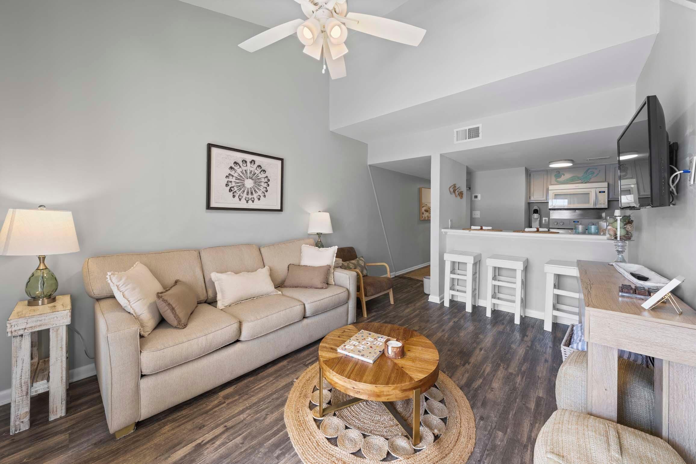 A living room with a sofa, coffee table, and a dining area with stools.