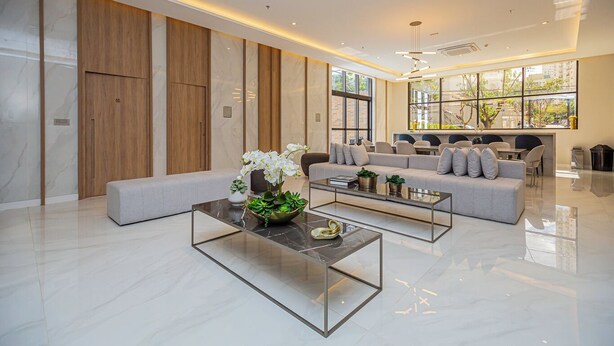A modern living room with a sofa, two coffee tables, and a decorative plant arrangement. - Flat c Piscina e Academia na Ch Cara Klabin (São Paulo)
