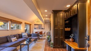 Un salon moderne avec un canapé, une table basse et un coin repas avec des chaises. On y trouve également une cuisine avec des meubles sombres et un plan de travail en bois.