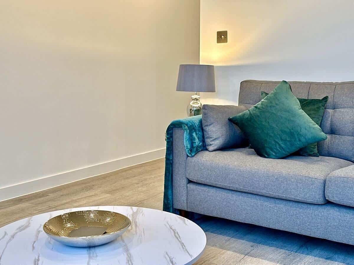 A modern living room with a grey sofa, a round coffee table, and a lamp.