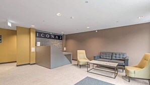 Eine Lobby mit einer Rezeption, zwei Sesseln, einem Sofa und einem Couchtisch.
