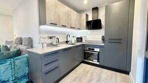Eine moderne Küche mit grauen Schränken, einer Mikrowelle, einem Wasserkocher und einem Backofen.
