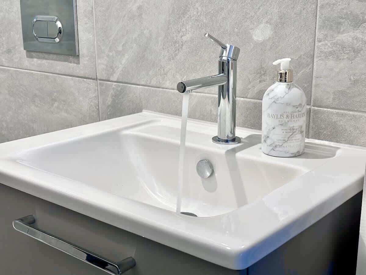 Un lavabo de salle de bain doté d’un robinet moderne, d’un distributeur de savon et d’un porte-serviettes.