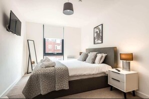 A bedroom with a bed, bedside table, lamp, and a framed picture on the wall. - Stunning Apartment With Balcony Walking Distance (York)