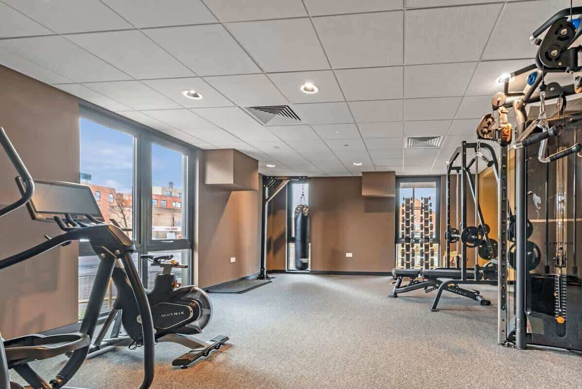 Une salle de sport équipée de tapis de course, d’appareils de musculation et d’un sac de frappe.