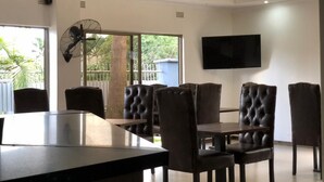 Un comedor moderno con barra, sillas de cuero y televisor de pantalla plana.