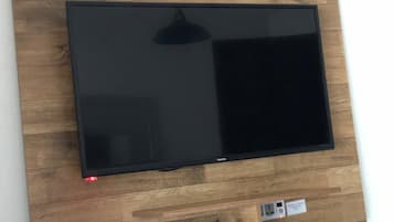 Un televisor de pantalla plana montado en una pared de madera con un estante debajo.