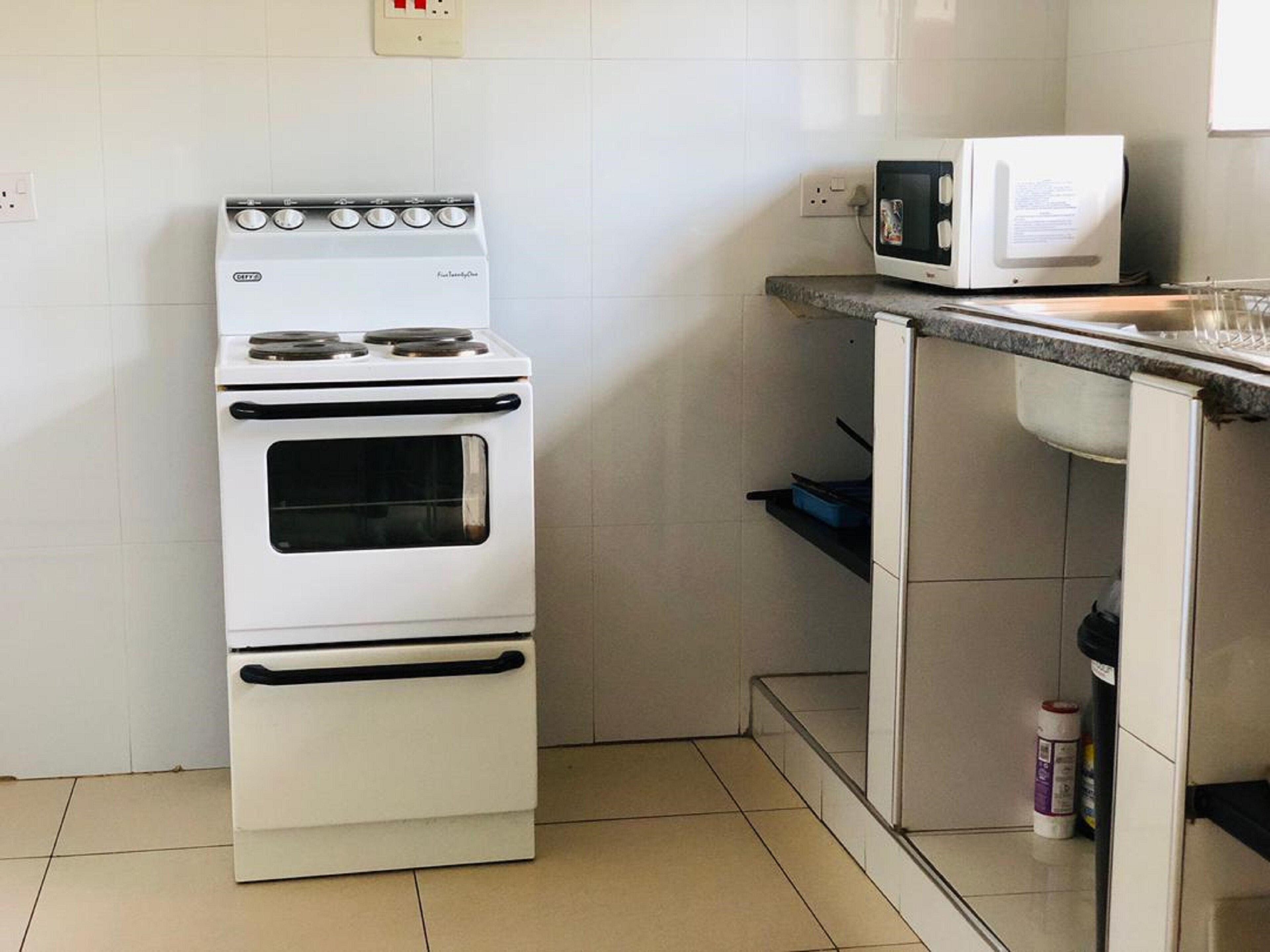 A kitchen with a white stove, a microwave, and a sink.