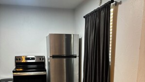 Cozinha compacta com geladeira, forno e micro-ondas de aço inoxidável.