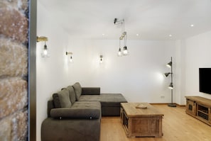 Ein modernes Wohnzimmer mit einem Ecksofa, einem Holztisch und Pendelleuchten.