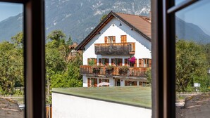 A two-story building with a balcony, surrounded by trees and mountains. - Apartment 'Josef' with Mountain View, Shared Garden and Wi-Fi (Garmisch-Partenkirchen)