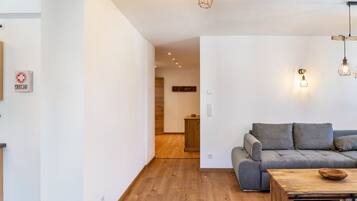 Een moderne woonkamer met een grijze bank, houten vloer en hanglampen.