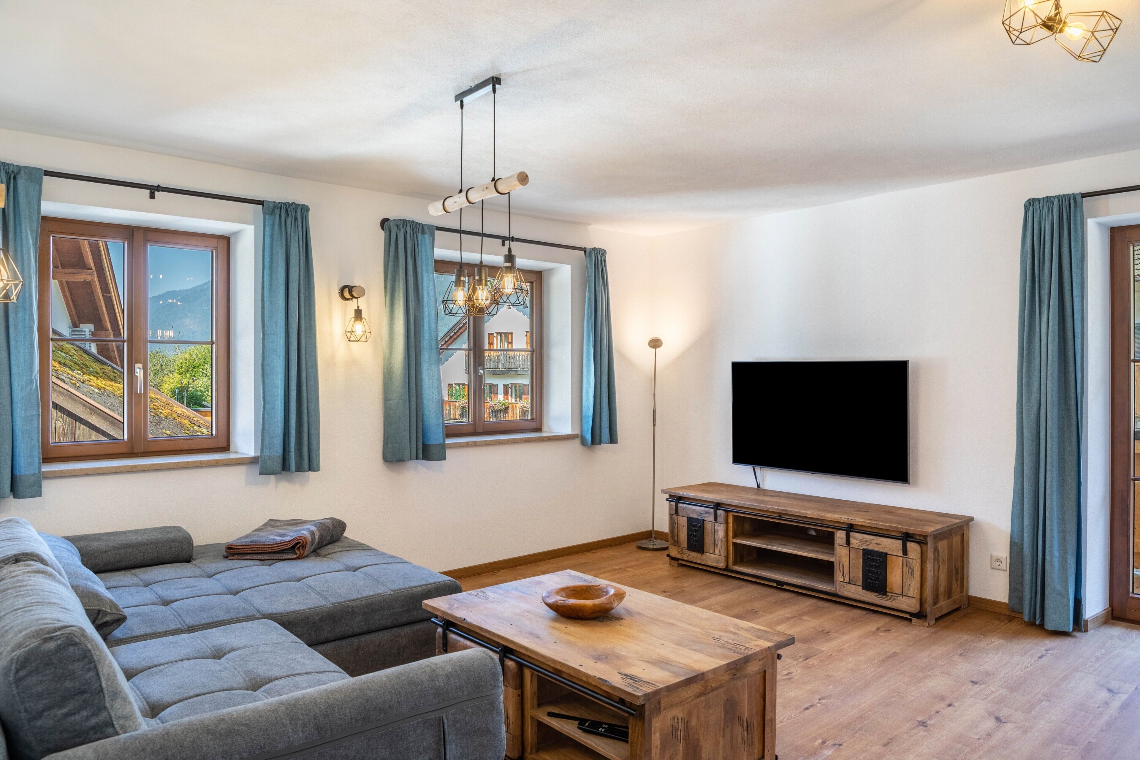 Un salon moderne avec un canapé, une table basse en bois et un téléviseur à écran plat.
