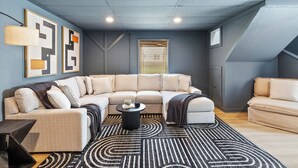 A modern living room with a sectional sofa, a coffee table, and abstract wall art. - 4BR Pineville Retreat - Private Pool - Fire Pit - Near Carowinds & Charlotte (Pineville)