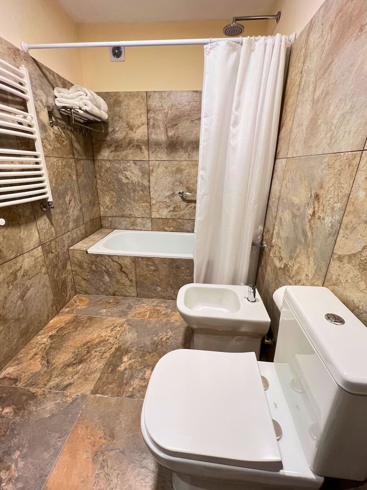 Un baño con bañera, inodoro y cortina de ducha.