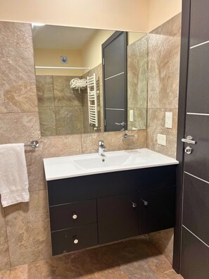 A bathroom with a white sink, dark cabinets, a towel rack, and a mirror.