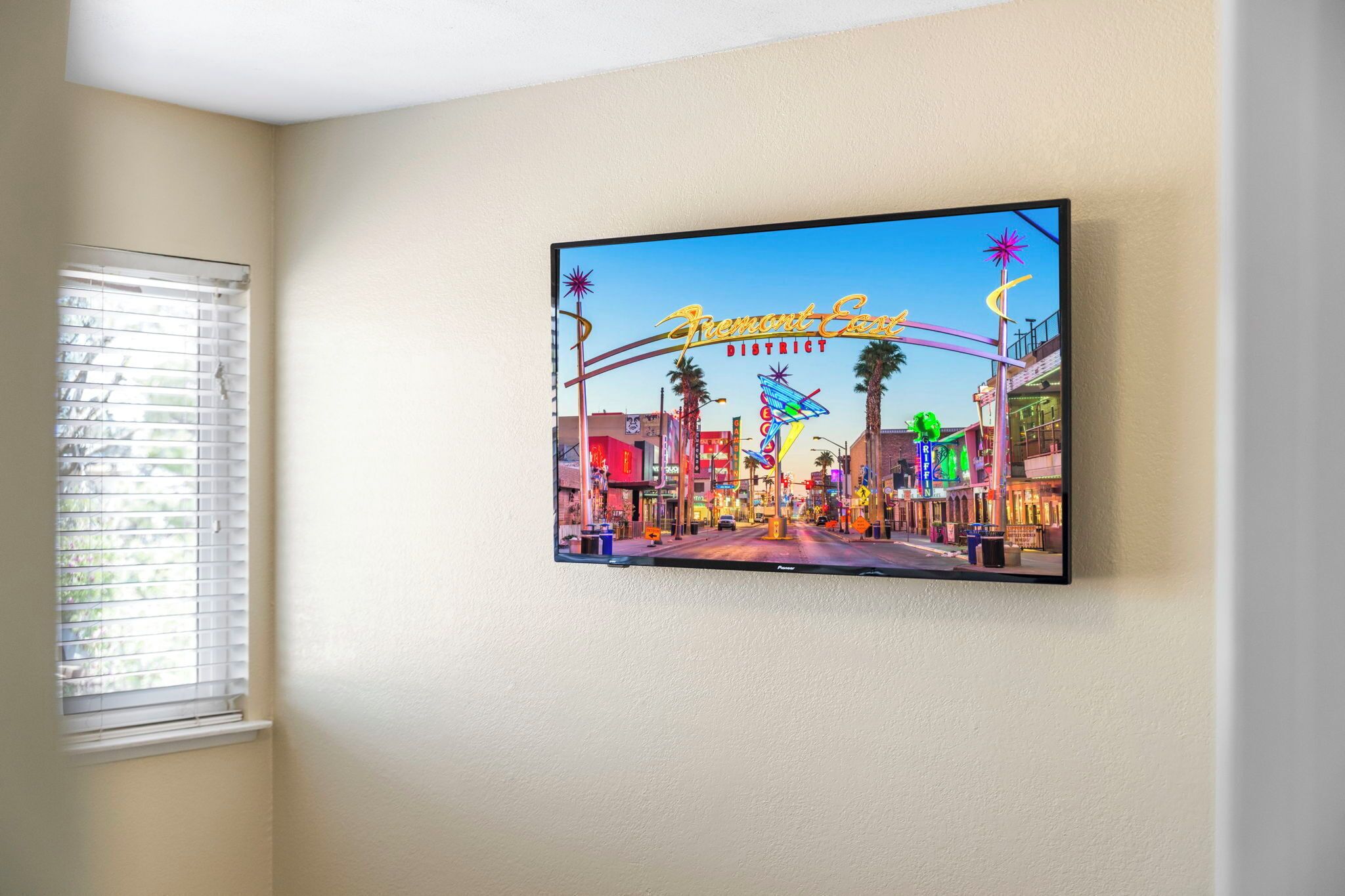 A television mounted on a wall displaying a neon sign for Fremont County.