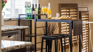 Une cuisine moderne avec un coin repas, comprenant un plan de travail en marbre, des chaises noires et un luminaire suspendu.