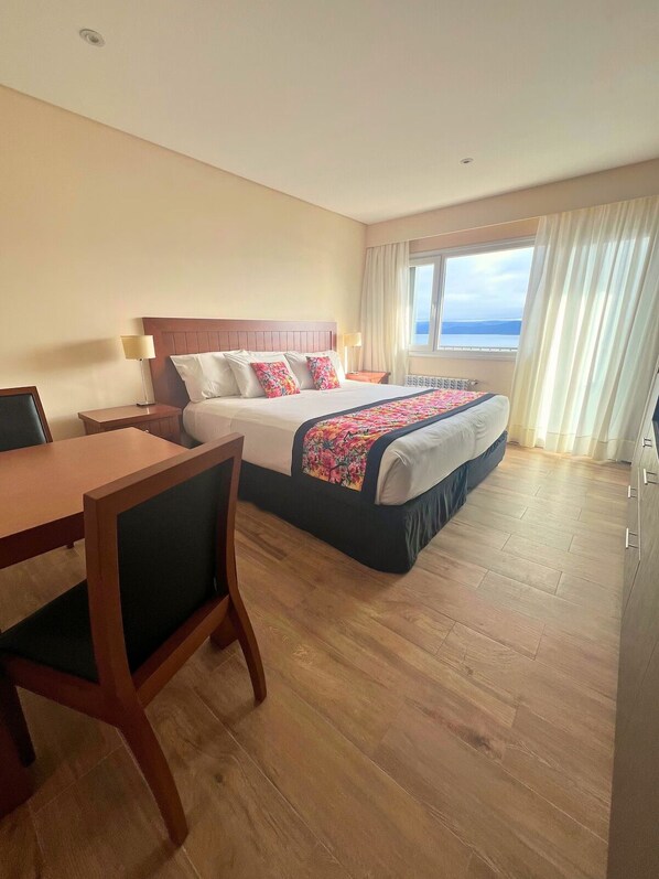 Habitación de hotel con cama, escritorio y vistas al mar.