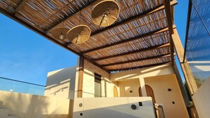 A modern building with a covered outdoor area featuring a wooden ceiling and woven ceiling fans. - Casa Hood Boutique Hotel (Isla Holbox)