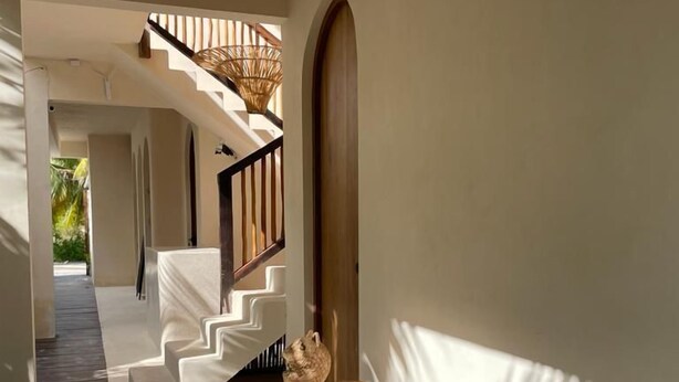 A modern interior with a wooden bench, a staircase, and a view of greenery outside. - Casa Hood Boutique Hotel (Isla Holbox)