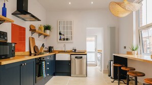 Une cuisine moderne dotée d’un îlot central, d’appareils électroménagers intégrés et d’un coin repas avec des tabourets.
