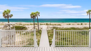 A wooden deck leading to a beach with palm trees and a lifeguard tower. - Luxury Gulf-front Retreat | Sleeps 24 | Private Pool (Port St. Joe)