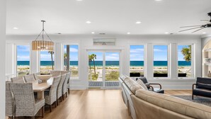 A spacious dining area with a view of the beach, a large window, and a ceiling fan. - Luxury Gulf-front Retreat | Sleeps 24 | Private Pool (Port St. Joe)