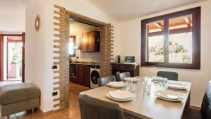 A dining area with a table set for four, a kitchen in the background, and a window with a view.