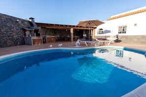 Una piscina con sillones de descanso y zona de barbacoa.