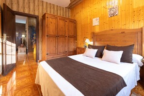 Una habitación con paneles de madera, una cama grande, una mesita de noche y un armario.