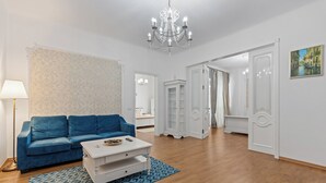 Een moderne woonkamer met een blauwe bank, een witte salontafel en een vloerkleed met een patroon.