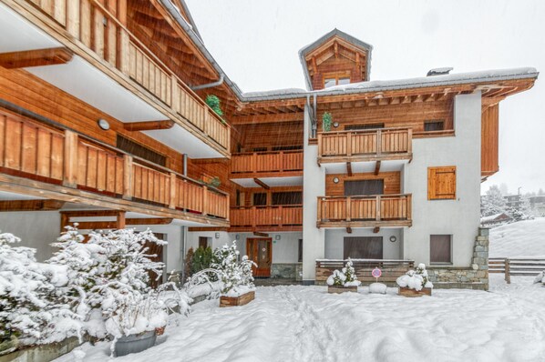 A multi-story wooden building with balconies, a stone base, and snow-covered surroundings.