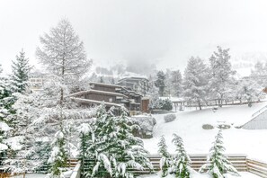 Un paysage enneigé avec des bâtiments, des arbres et une piste de ski.
