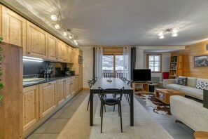 A modern kitchen with wooden cabinets, a dining table, and a TV.