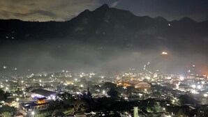 Une vue nocturne d’une ville, avec une montagne en arrière-plan.