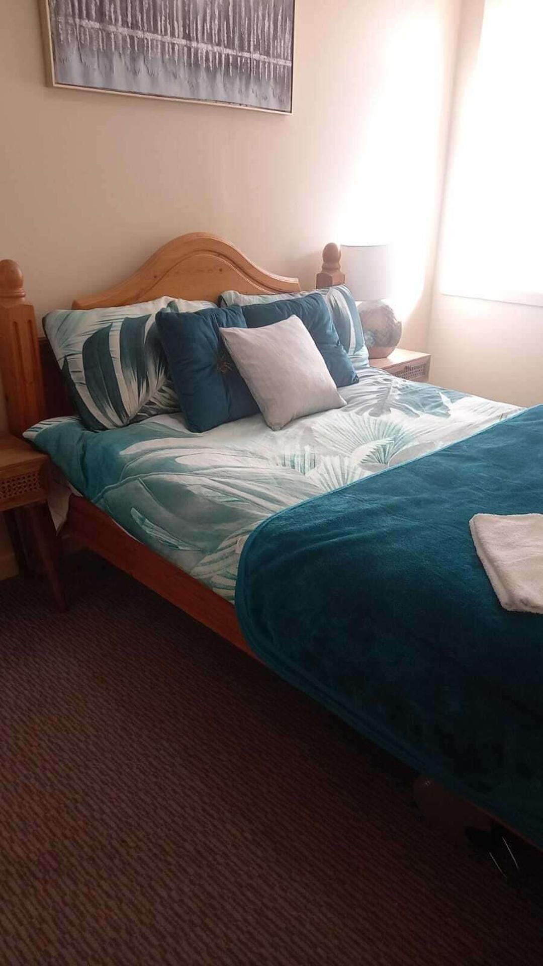 Un letto con una testiera in legno, numerosi cuscini e una coperta blu.